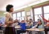 Teacher BUSTED After 5 Fake ‘Active Shooter’ Alerts Teacher engaging with students raising hands in a classroom