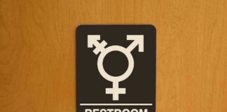 Restroom sign with gender-inclusive symbol on wooden door