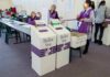 Election workers near ballot boxes in a polling station