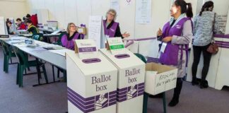 Election workers near ballot boxes in a polling station
