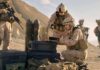 Soldiers in desert setting prepare equipment near rugged hills