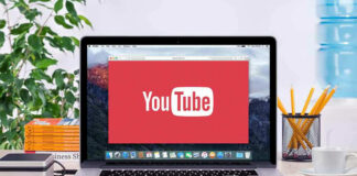 YouTube logo on a laptop screen on desk.