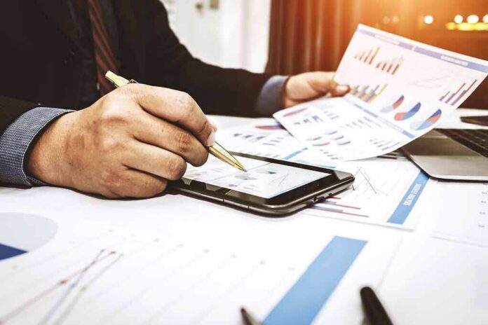 Businessperson analyzing charts with tablet and papers