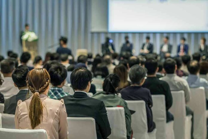 shutterstock_1029731890 Audience listening to a panel discussion in a conference hall
