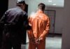 Police officer escorting handcuffed inmate in orange jumpsuit