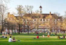 Students relaxing on a campus quad in front of a brick academic building