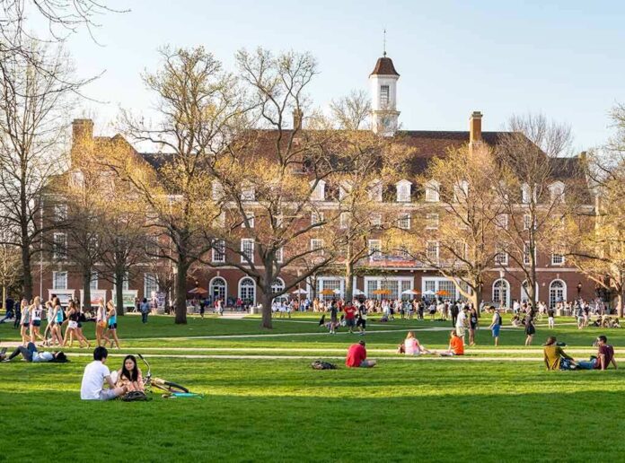 shutterstock_1037739901 Students relaxing on a campus quad in front of a brick academic building