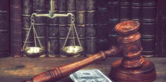 Judge's gavel beside cash and scales of justice on a wooden desk