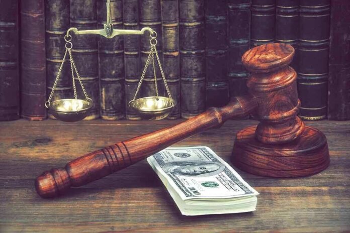 Judge's gavel beside cash and scales of justice on a wooden desk