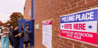 Voters line up outside a brick building polling place