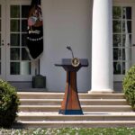 Trump Freezes Bills Until GOP Delivers Podium with presidential seal in a garden colonnade