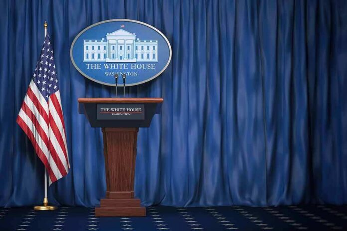 shutterstock_1165119412-3 White House press briefing podium with U.S. flag and blue curtain
