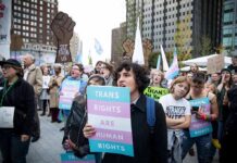Crowd of protesters holding trans rights signs at a city rally