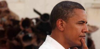 Barack Obama in profile, touching his chin thoughtfully