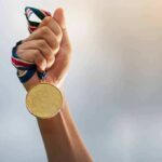 Hand holding a gold medal with ribbon