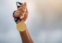 Hand holding a gold medal with ribbon