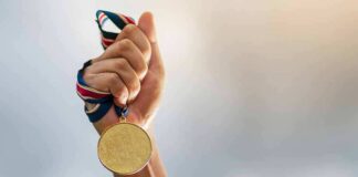 Hand holding a gold medal with ribbon