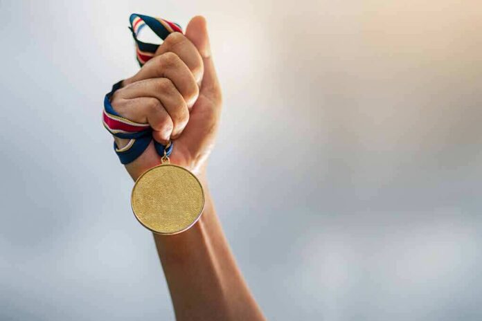 Hand holding a gold medal with ribbon