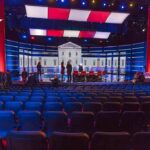 Debate stage with red and blue lighting and empty audience seats