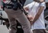 police officer handcuffing a person beside a vehicle