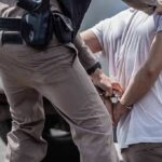 Bodycam Footage Debunks Claims Made by Illegal Shot by ICE Officer police officer handcuffing a person beside a vehicle