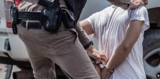 police officer handcuffing a person beside a vehicle
