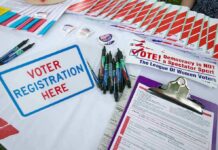 Voter registration table with forms, pens, and informational materials