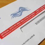 DOJ Investigates Millions In Dem Campaign Spending Mail-in ballot envelope with red label on wooden table