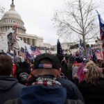 Military Oath Collides With DC Handcuffs crowd with flags gathered outside the U.S. Capitol building