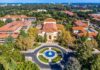 Aerial view of a campus building with red-tile roofs and a round fountain plaza
