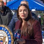 Socialist Mayor Faces RECALL Over Criminal Allegations Woman speaking at outdoor press event with microphone and seal