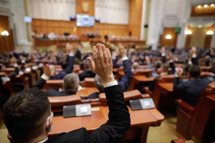 Legislators raise hands during a vote in a large chamber