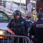 Police officers in tactical gear near a patrol vehicle at night