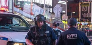 Police officers in tactical gear near a patrol vehicle at night