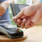Hand tapping a credit card on a payment terminal
