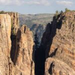Steep canyon cliffs with a narrow chasm and scattered pines