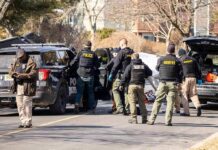 Helicopter Fired On – Town Locks Down Police and sheriff officers gather around vehicles on a suburban street