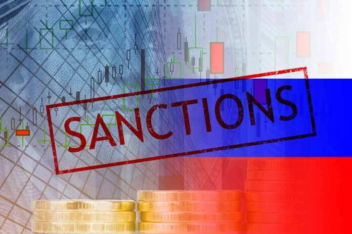 shutterstock_2129803259 Sanctions text over financial chart and flag with coin stacks