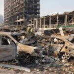 Burned cars amid rubble in a destroyed urban area