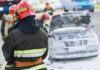 Firefighter near foam-covered car with open hood