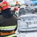 Firefighter near foam-covered car with open hood