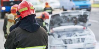 Firefighter near foam-covered car with open hood