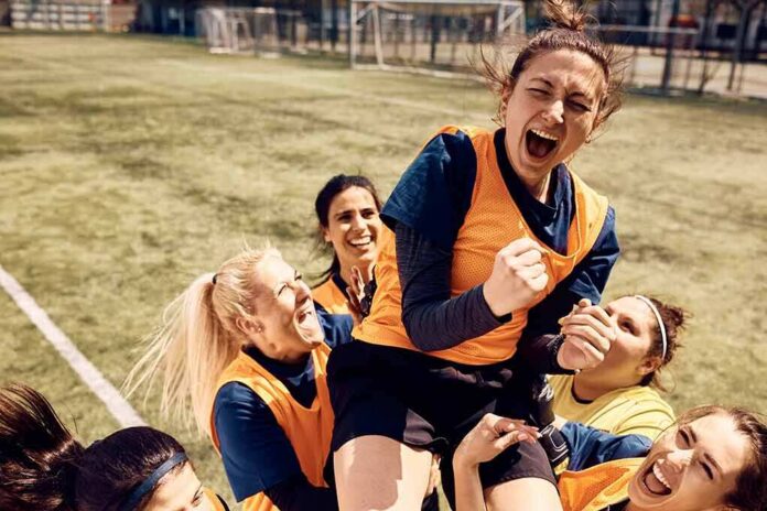 Women's soccer teammates celebrate lifting a player