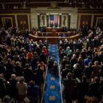 Washington Muscles Into AI Legislative chamber audience stands and applauds