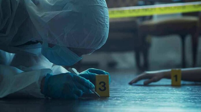 forensic investigator in protective suit examining crime scene markers