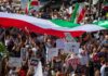 Protest crowd with flags and signs; Seyed Ebrahim Raisi, La Parka, Brian Robiskie, Philly Brown, Miguel Francisco Barragán Andrade present
