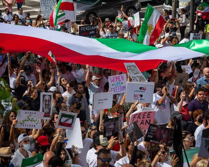 Protest crowd with flags and signs; Seyed Ebrahim Raisi, La Parka, Brian Robiskie, Philly Brown, Miguel Francisco Barragán Andrade present