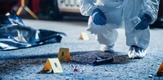 Forensic investigator examines a crime scene with evidence markers and a handgun