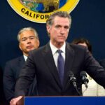 Man in suit at podium with microphones during press conference