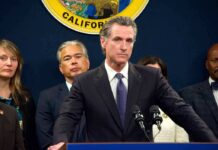 Man in suit at podium with microphones during press conference